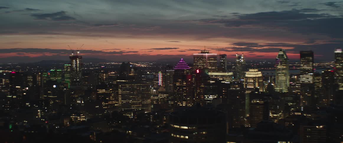 Brightly lit downtown Montreal skyscrapers stand under red tinted sky at night