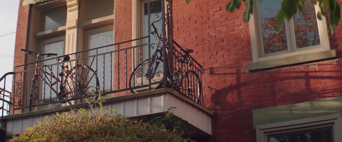 Two bicycles sit locked on an apartment building balcony