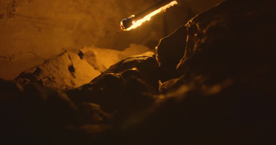 A burning metal rod moves over rocks