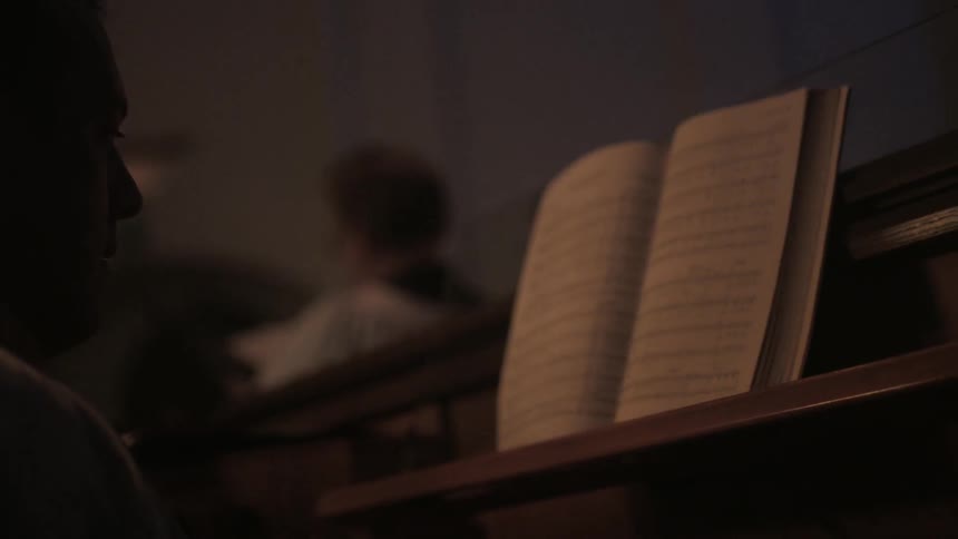 A musician reads sheet music at a piano