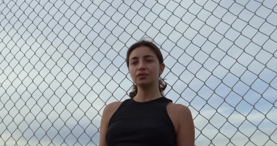 A woman is standing near a fence in summer