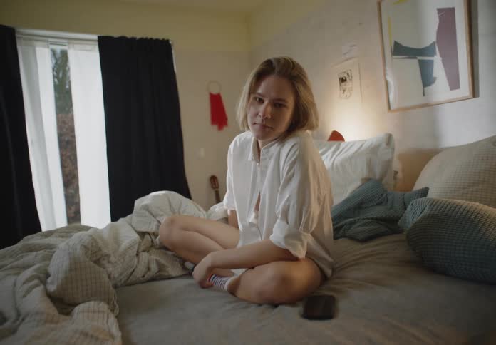 A young woman is sitting on her bed in the morning