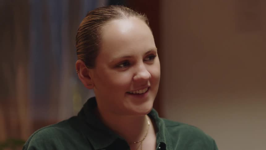 Woman near curtained window smiles broadly