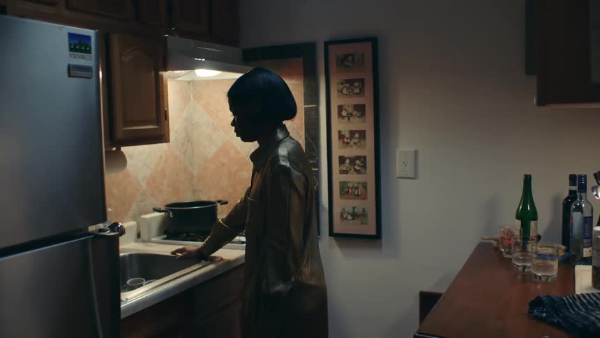 A woman leans against the stove in her kitchen