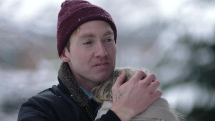 A man holding a child with blonde hair slightly smiling into the distance