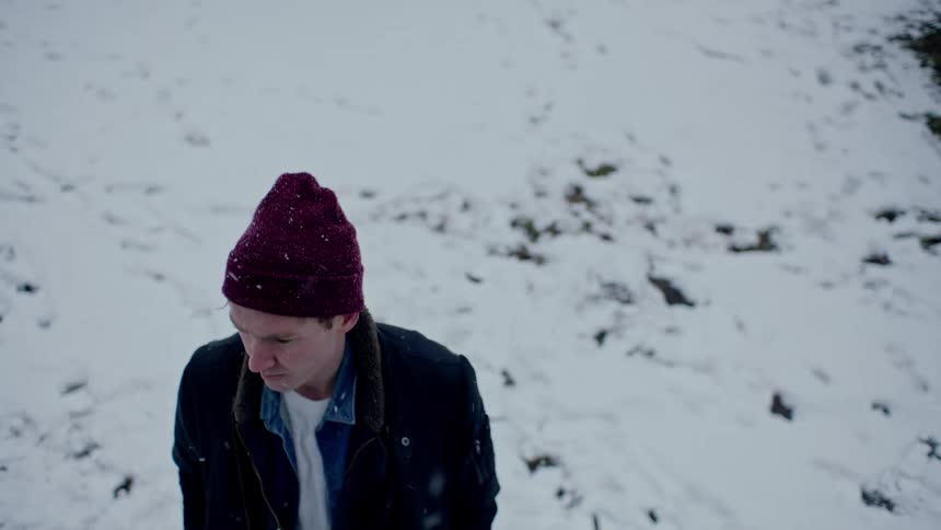 A man is walking outdoors while it is snowing