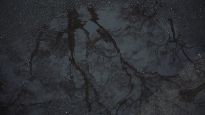 A man walks through a puddle in a parking lot