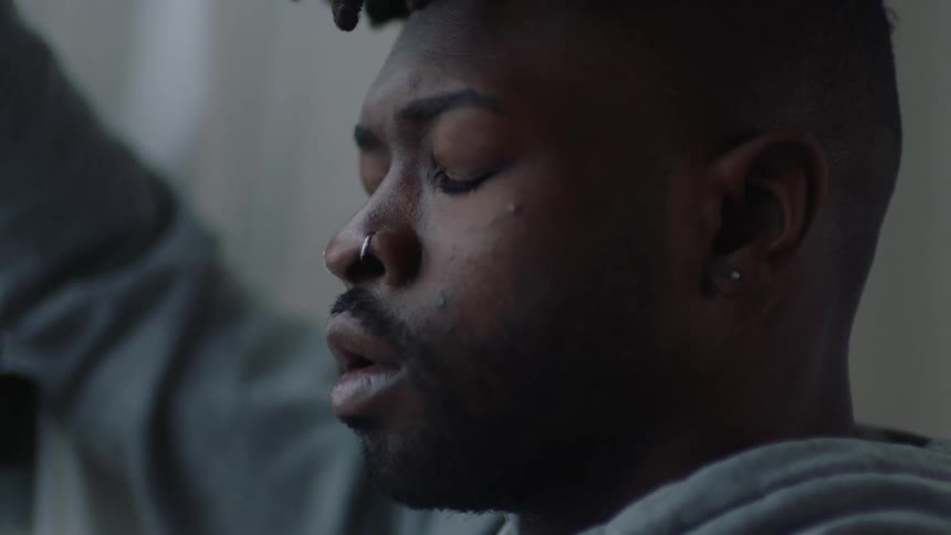 A man stands and takes multiple deep breaths while closing his eyes