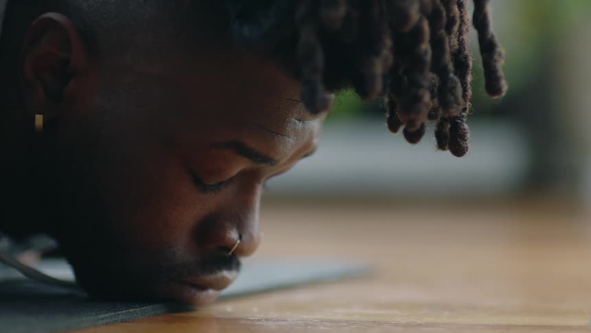 A man rests his chin on the edge of a yoga mat