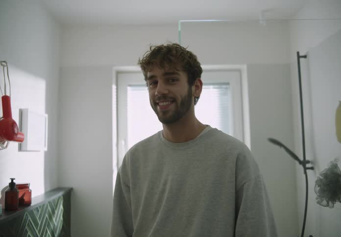 A young man is standing inside of his home and smiling