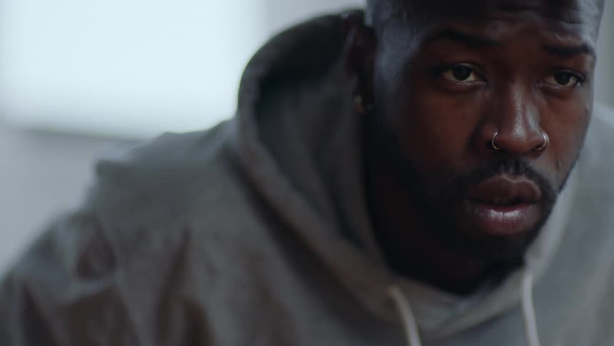 Man with beard nose piercing and gray hoodie works out in the gym