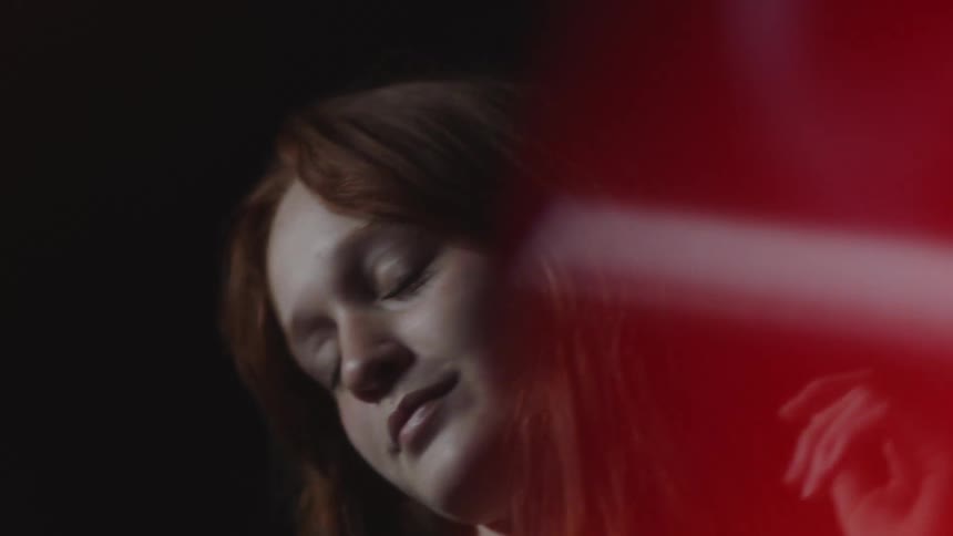 A red headed female dances while looking forward and smiling