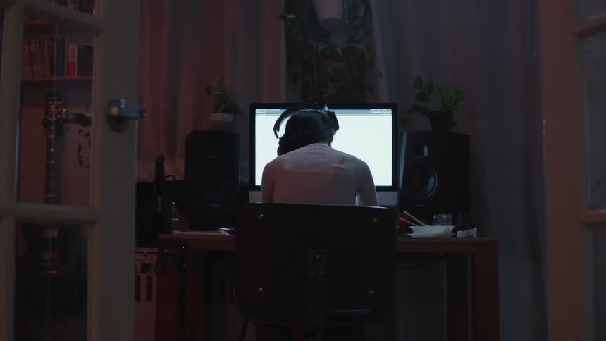 A female sits at her desk with her back towards the camera looking at a computer monitor