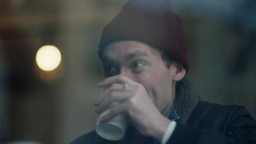 A young man is drinking some coffee in the middle of the day time