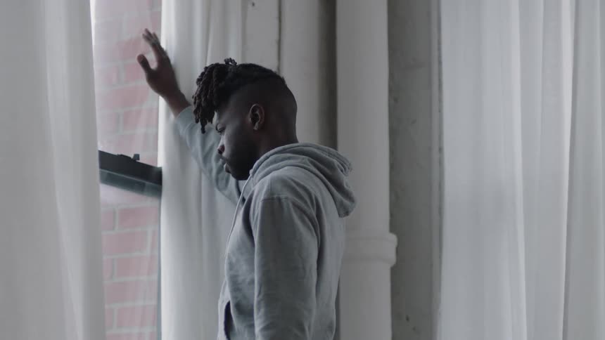 A young black man is inside of his home in the middle of the day time