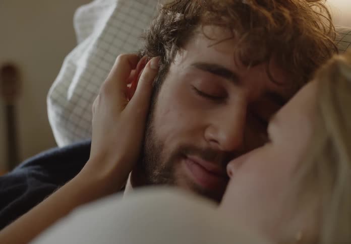 A young couple is laying in bed together in the morning