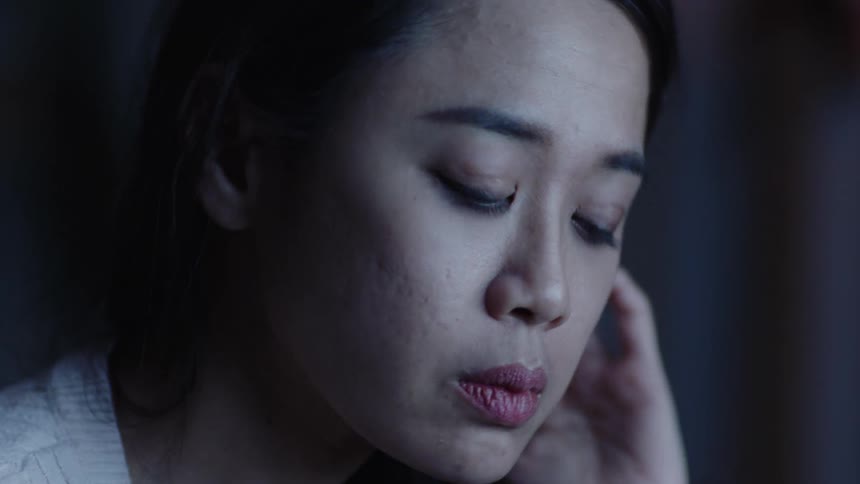 A close up of a womans face with her hands on it looking stressed then putting her glasses on