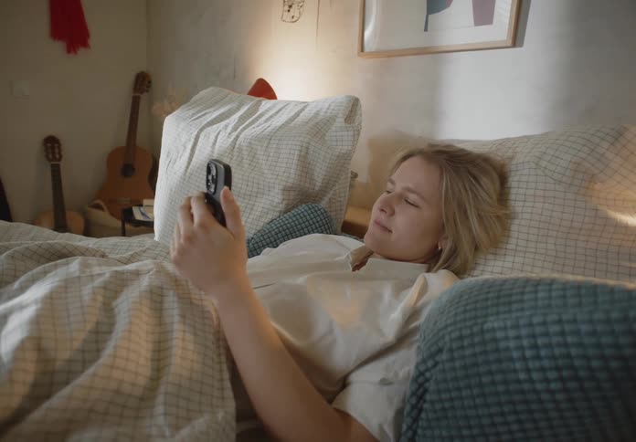 A woman is looking at her phone in bed