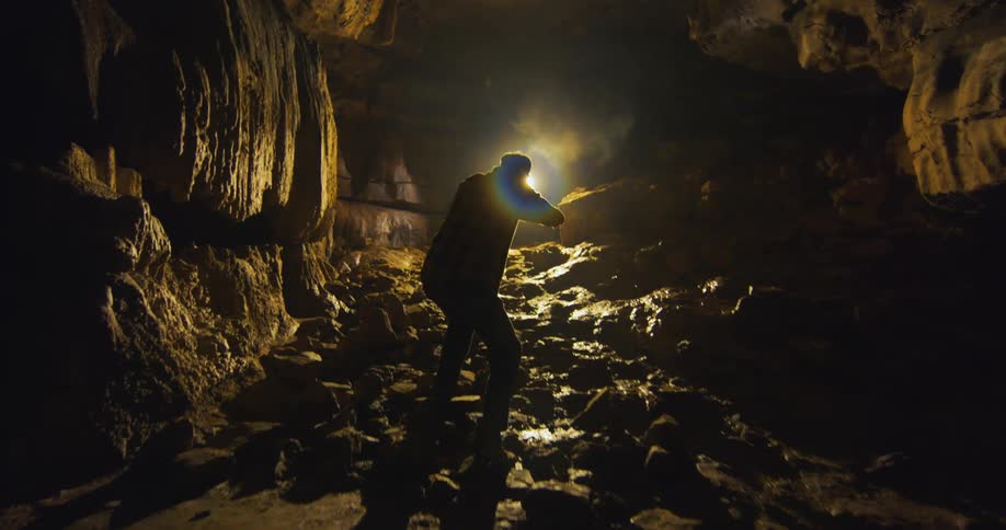 A man is searching through the dark cave