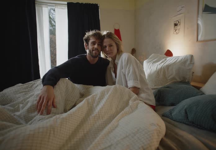 Man and woman are sitting in bed together during the day time