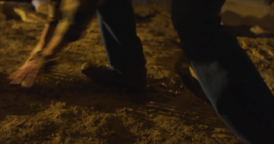 Man uses his hands to balance while moving up uneven dirt and rock slope