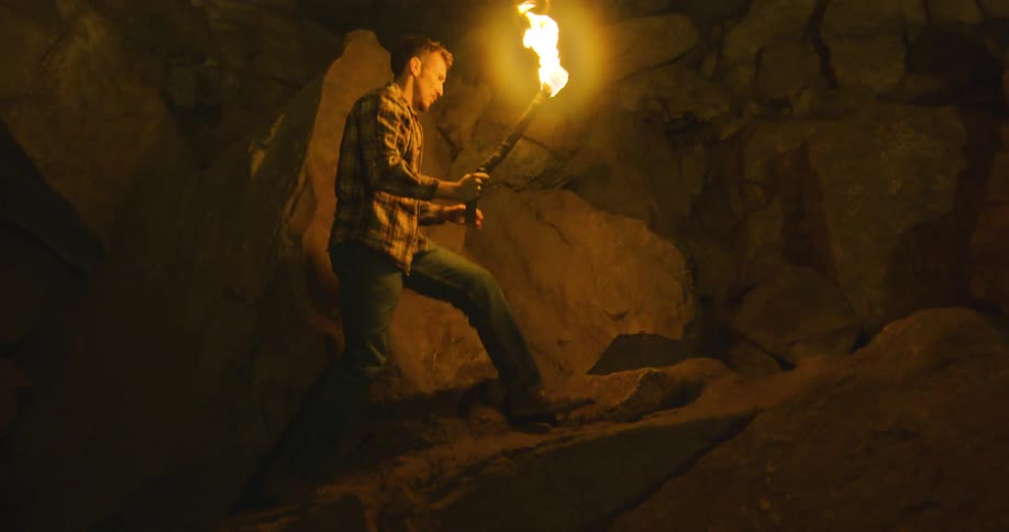 A man is hiking through a cave during the night time