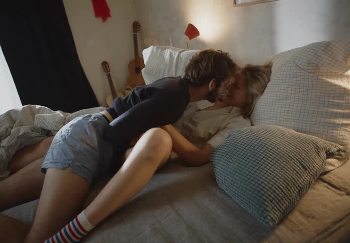 Man and woman make out on bed in bedroom playing with each other
