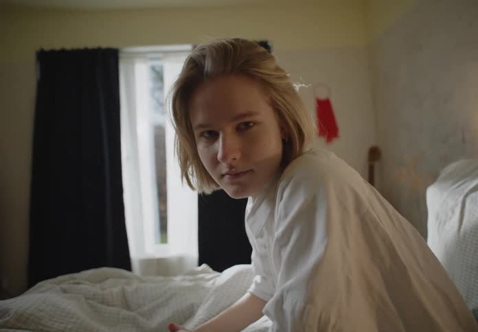 A close up of a womans face in bed playing with her hair