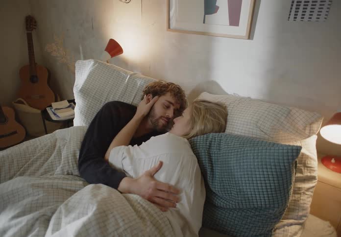 A man and woman holding each other sentimentally in their bed