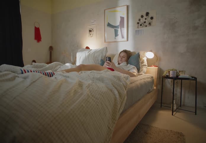A woman is laying down and texting on her phone