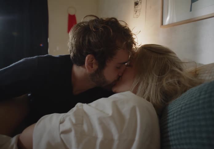 A man and woman touching and kissing each other sentimentally on their bed in the morning