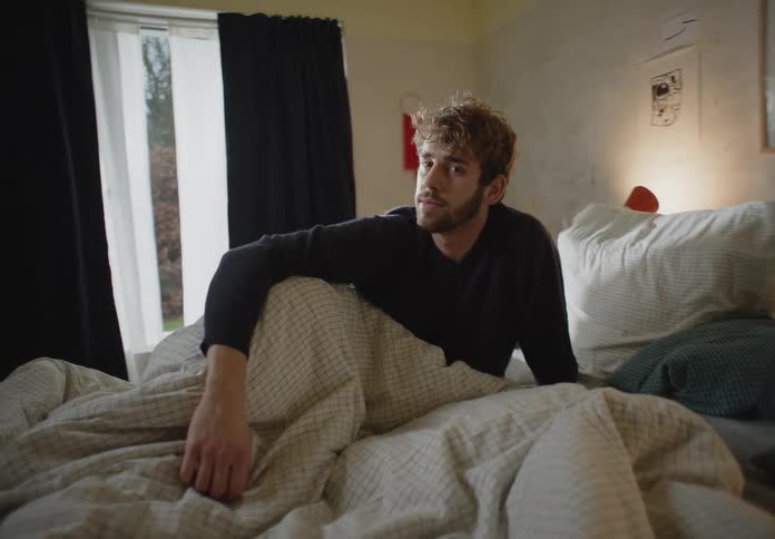 Portrait of a man sitting on his bed during the daytime