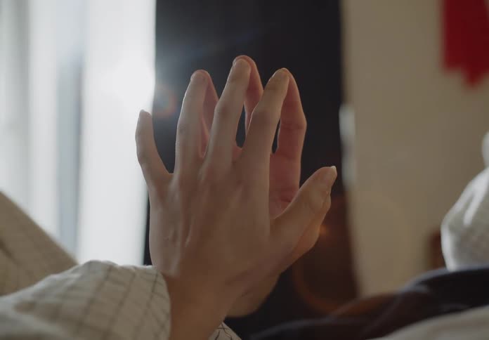 Man and woman are holding hands and laying in bed