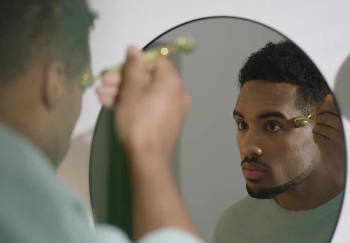 A man is smoothing his face with a jade roller