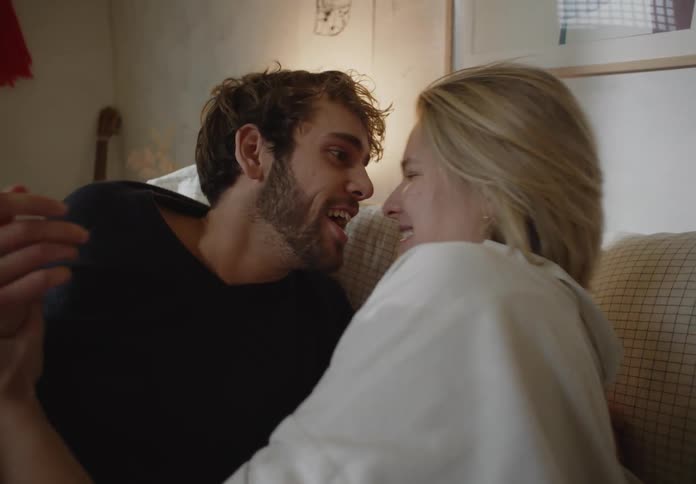 A man and woman laying around in a bed