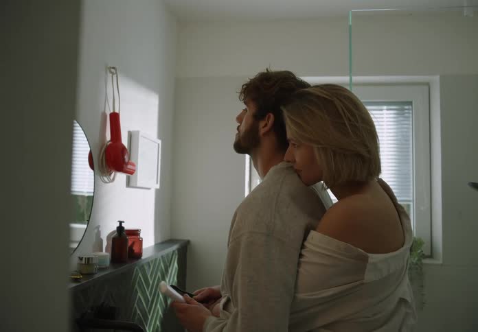 Woman back hugs man as he gets ready to brush his teeth