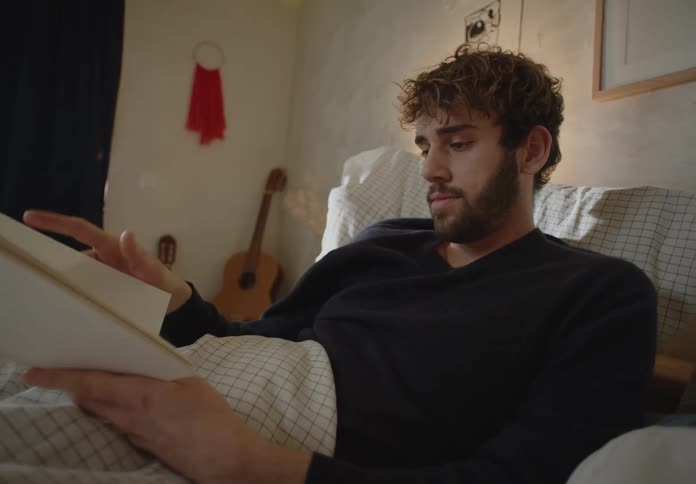 A man is laying in bed and reading a book