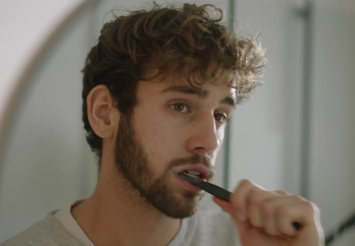 A man is brushing his teeth in the bathroom
