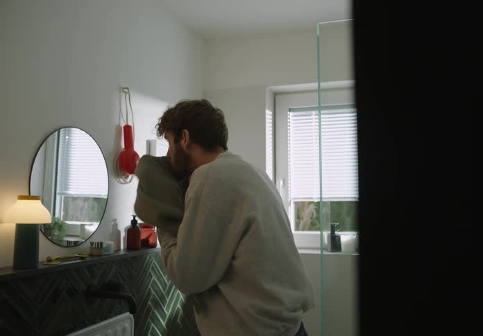 A young white man is washing his face in the bathroom