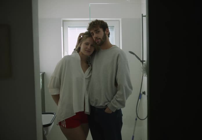 A man and woman standing holding each other in their bathroom