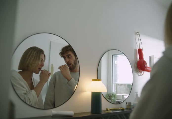 Couple brushing their teeth cuddles and smiles in bathroom
