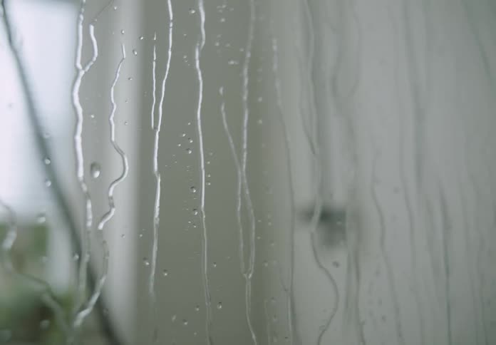 Rain is pouring down a window during spring