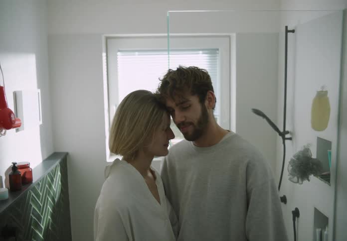 A man and woman nuzzling each other and then the man kisses her on the forehead