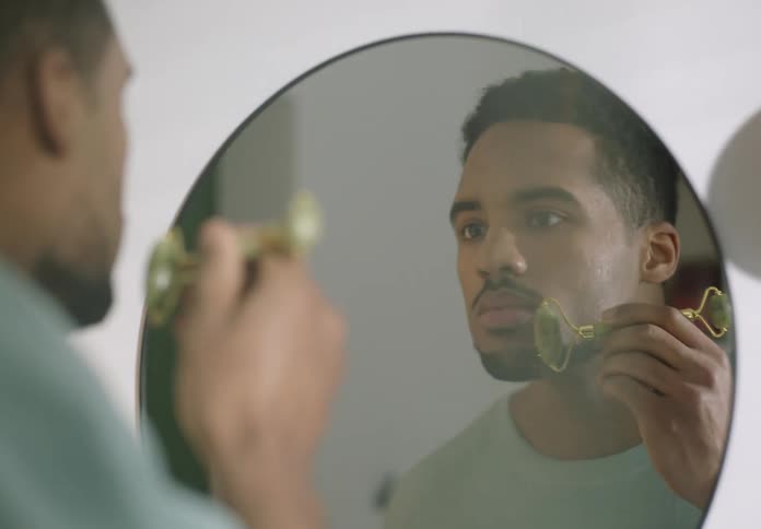 A man is smoothing his face with a skin tool
