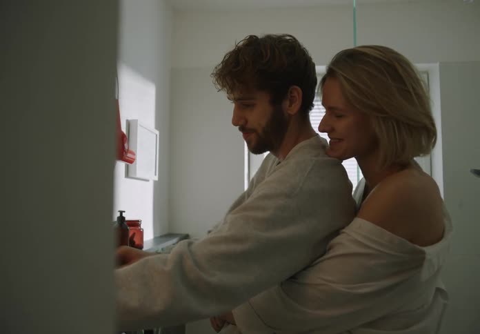 A woman hugs a man before he brushes his teeth