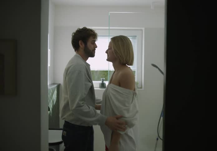 Couple in bathroom kiss and cuddle playfully before the woman gets ready to brush her teeth