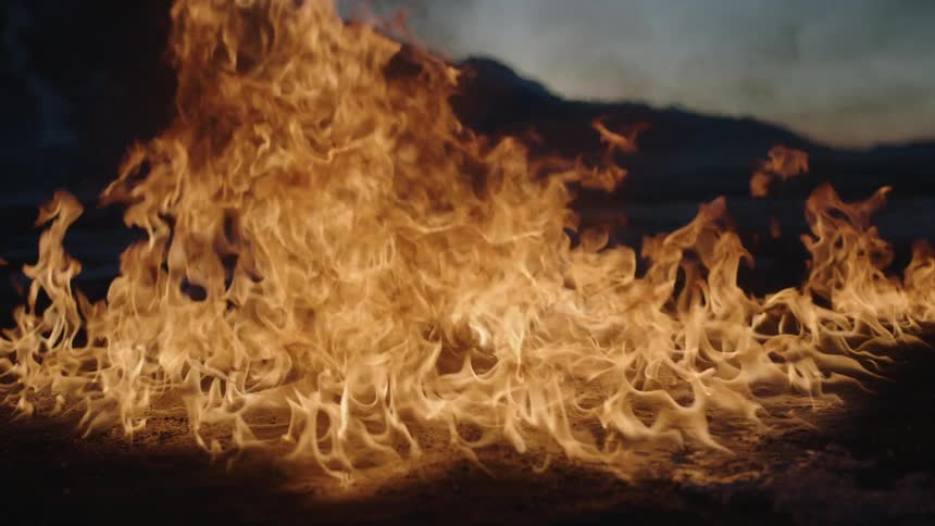 Fire rages on a field at dawn