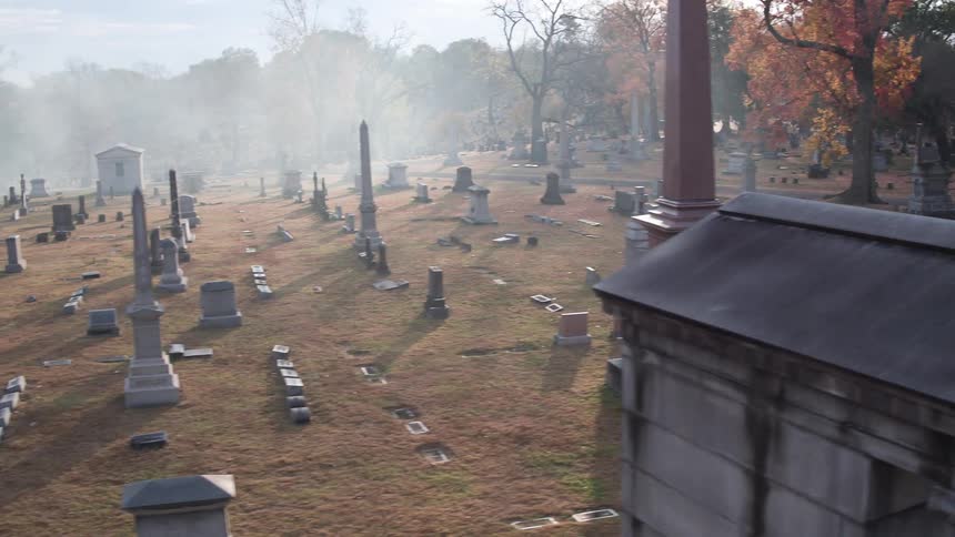 The sun shines over a foggy cemetery