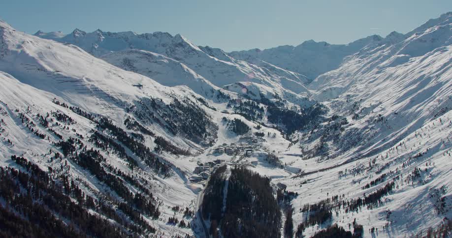 A blanket of snow covers trees along the side of a mountain range