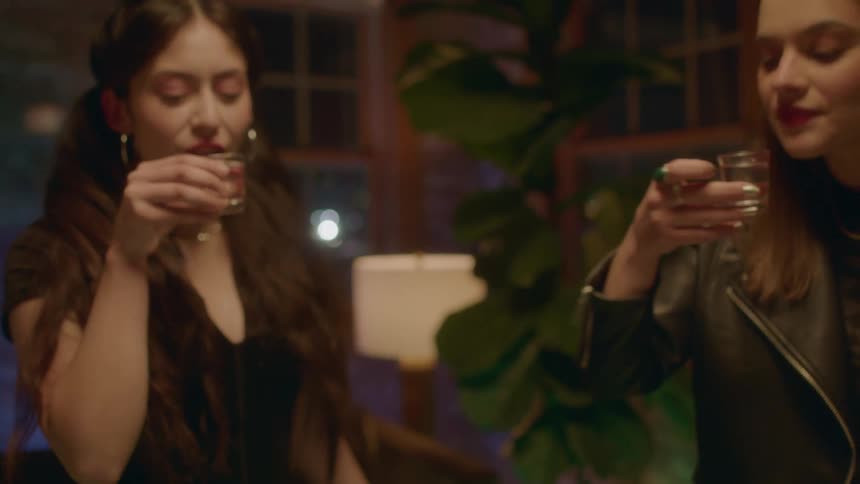 A group of friends toast their drinks before downing shots